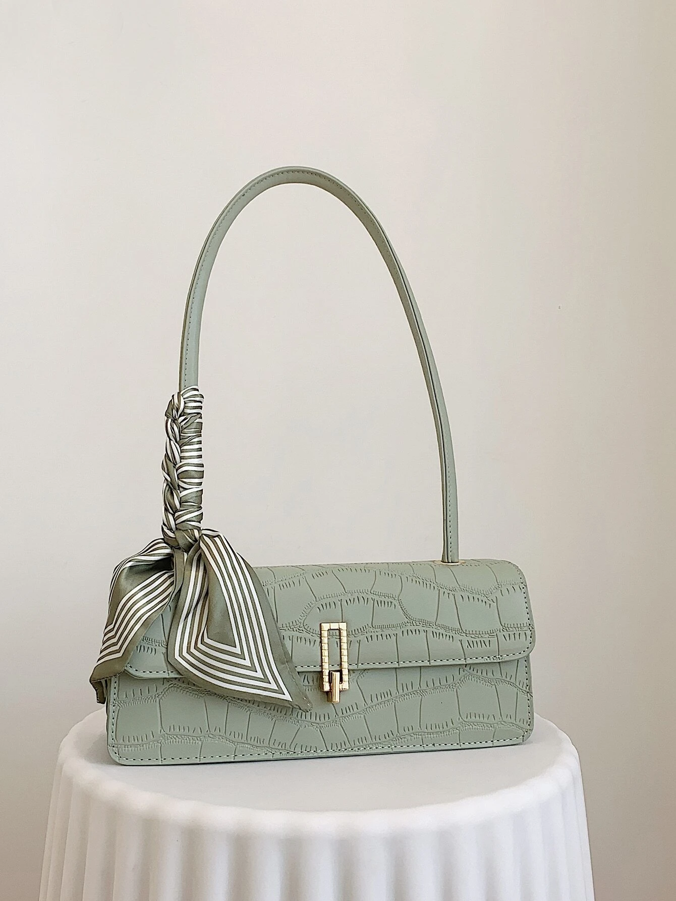 Crocodile embossed flap square bag with twilly decoration. This accessory blends sophisticated texture with stylish embellishments, offering a chic and visually appealing way to carry your essentials.