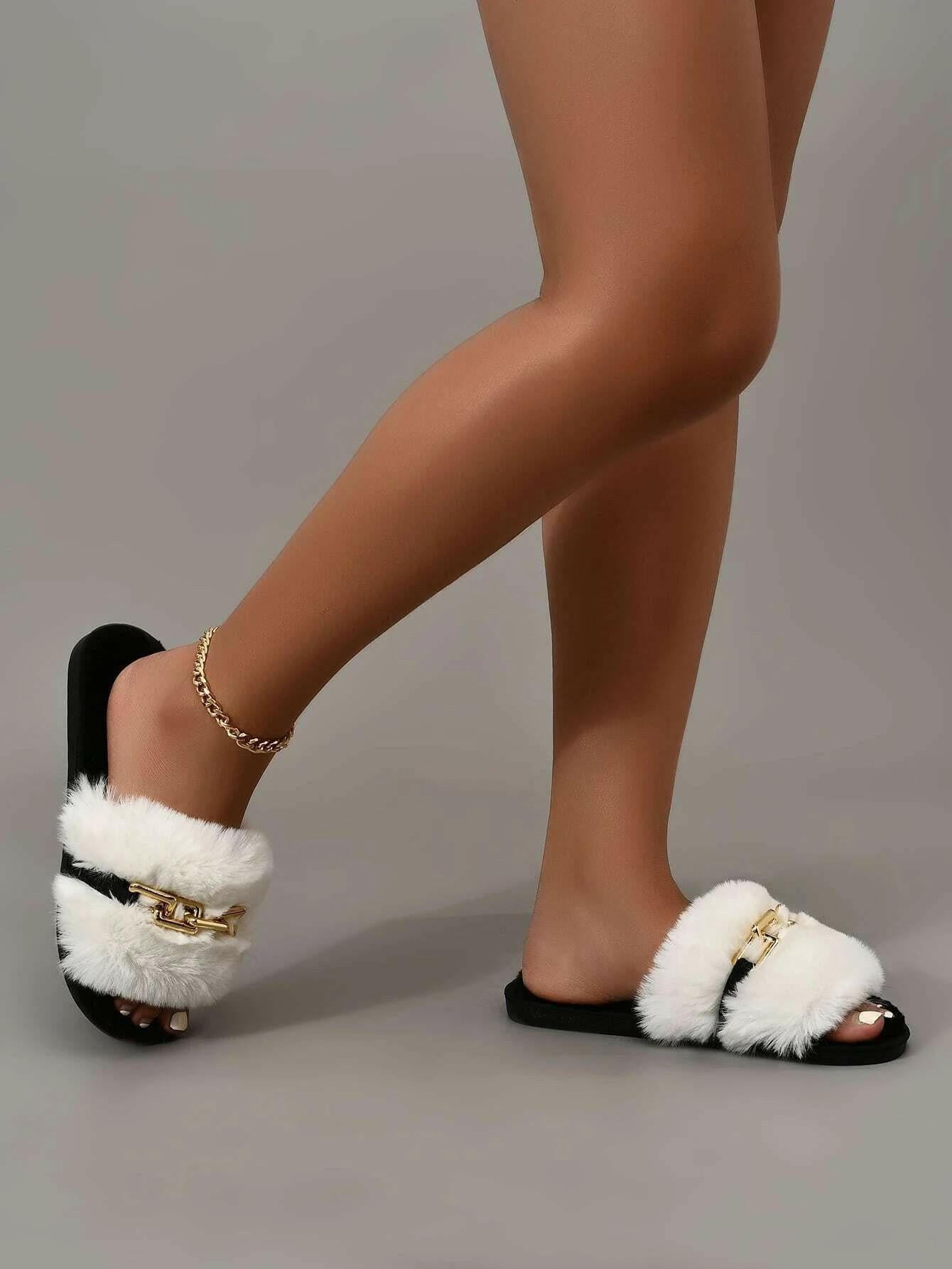 Fuzzy slippers enhanced with chain embellishments, blending comfort with a hint of elegance. The slippers showcase a fuzzy texture that envelops the feet in warmth, while dainty chains provide a stylish decorative element, perfect for indoor relaxation.