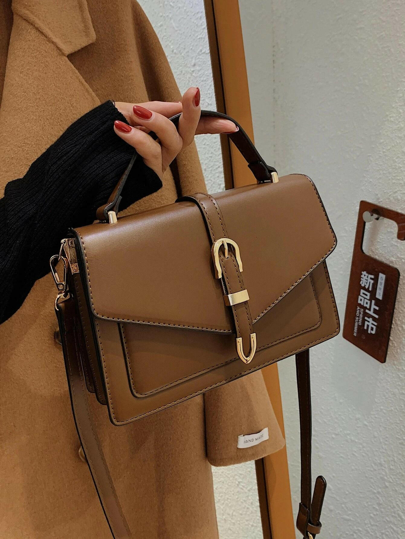 Square bag with flap closure and buckle decoration. This stylish accessory blends modern design with classic elements, offering both functionality and a fashionable touch.