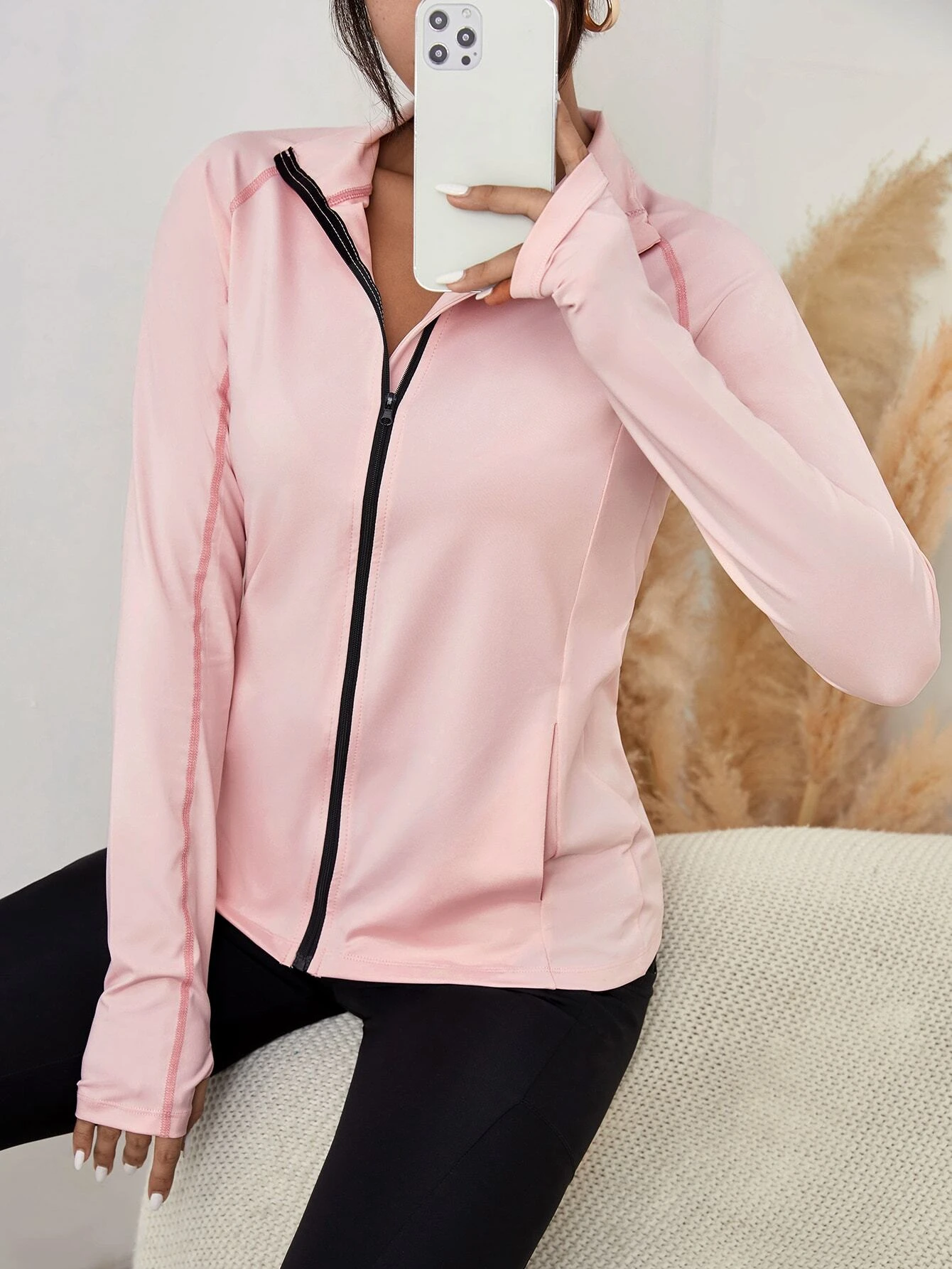 Image of a zip-up sports jacket with slant pockets and thumb holes. The jacket is designed to provide warmth during physical activities and features slant pockets and thumb holes for added functionality.