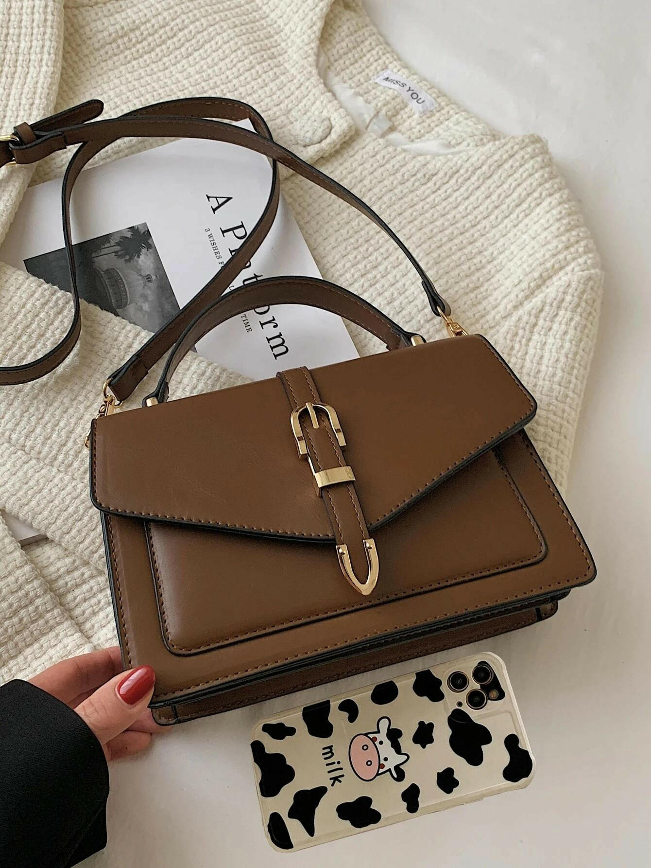 Square bag with flap closure and buckle decoration. This stylish accessory blends modern design with classic elements, offering both functionality and a fashionable touch.