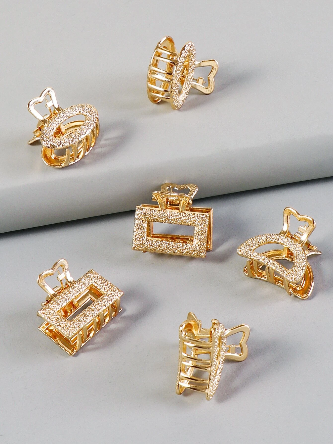 A set of six metallic hair claws, providing a sleek and modern way to secure and style your hair with a touch of shine.
