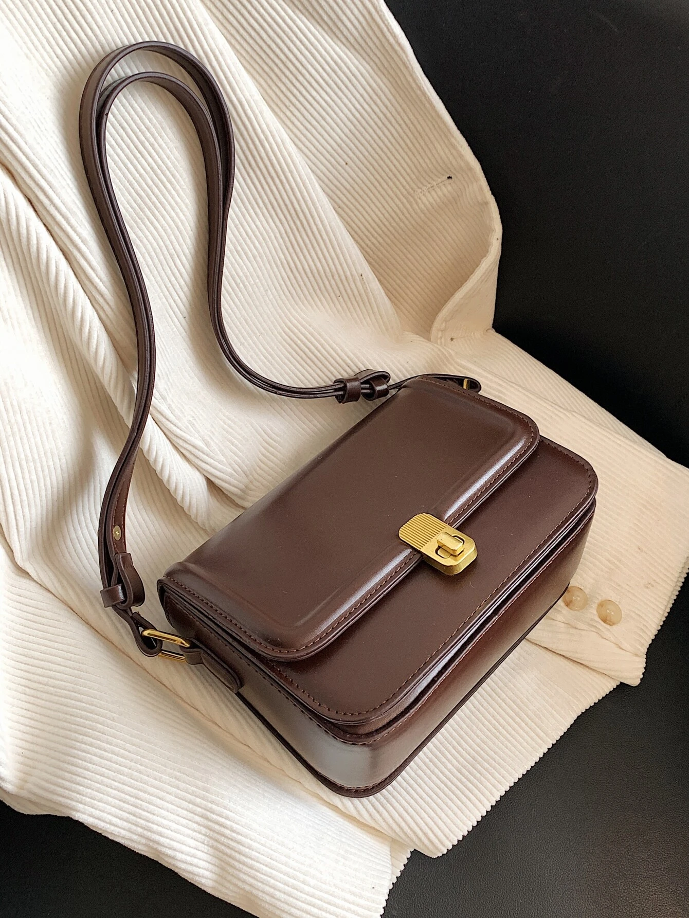 Square bag with twist lock flap closure. This accessory offers a chic and stylish way to carry your essentials, featuring a secure twist lock that enhances its functionality.