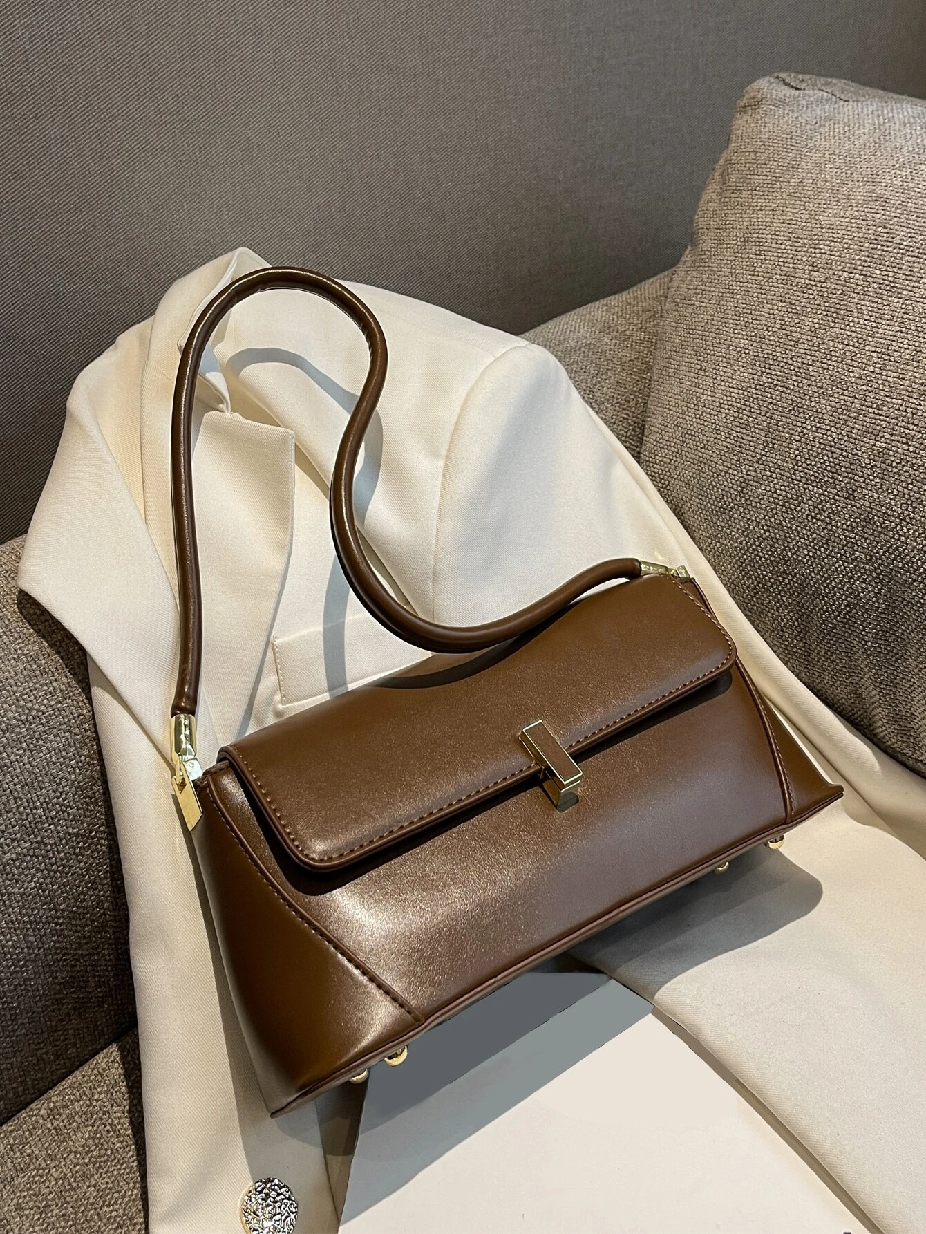 Flap baguette bag adorned with metal decorative elements. This accessory blends modern design with stylish embellishments, offering a chic and eye-catching way to carry your essentials.