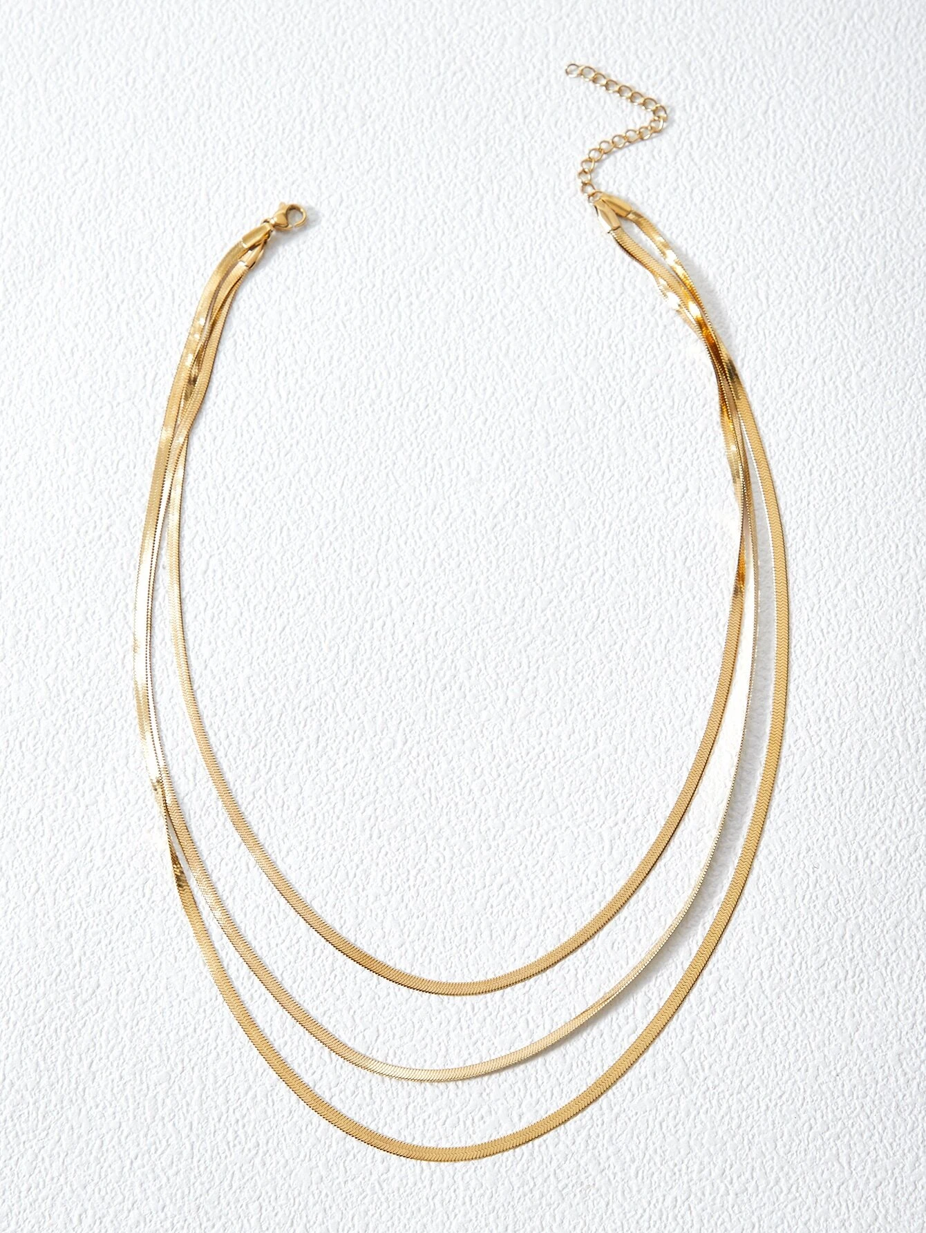 A layered necklace with a minimalist design. The necklace features delicate chains arranged in layers, creating a simple and elegant look. This accessory is modern and versatile, adding a touch of understated sophistication to various outfits